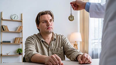 Пациент на сеансе гипноза Мужчина смотрит на ручные часы в руке